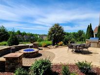 Wonderful backyard stone patio including a built-in fire pit and outdoor dining and built-in stainless steel grill at 305 Hemlock Bluff Ct, Denver, NC 28037