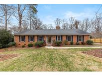 Charming brick home featuring a well-manicured lawn, mature trees, and classic blue shutters at 410 Deerwood Dr, Gastonia, NC 28054