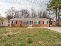 Charming brick home featuring a manicured lawn, black shutters and a brightly painted front door at 608 E Matthews St, Matthews, NC 28105