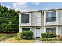 Two-story townhome featuring a white front door, lawn, and mature landscaping at 11020 Carmel Crossing Rd, Charlotte, NC 28226