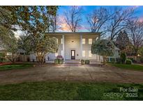 Stately white home with grand columns, manicured landscaping, and a circular driveway at dusk at 1225 Providence Rd, Charlotte, NC 28207