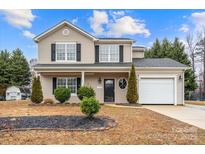 Charming two-story home with light siding, black shutters, well-manicured landscaping and an attached garage at 130 Valley Glen Dr, Troutman, NC 28166