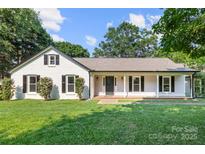 Charming home featuring a covered front porch, white painted brick and lush green lawn at 3501 Weddington Rd, Matthews, NC 28105