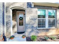 Charming brick home featuring a welcoming arched entryway, decorative wreath, and vibrant potted flowers at 1244 Madison Towns Ln, Charlotte, NC 28209