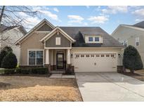 Charming home featuring a two-car garage, stone accents and a manicured lawn on a sunny day at 214 Blossom Ridge Dr, Mooresville, NC 28117