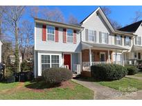 Charming two-story townhome with red door and shutters, complemented by mature landscaping and a well-maintained lawn at 6423 Windsor Gate Ln, Charlotte, NC 28215