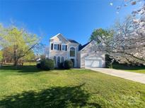 Charming two-story home with a well-manicured lawn and blooming trees under a clear blue sky at 9135 Stoney Corner Ln, Charlotte, NC 28210