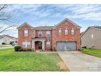 Charming two-story brick home with well-maintained lawn and inviting entrance and attached two car garage at 9205 Camberwell Rd, Mint Hill, NC 28227