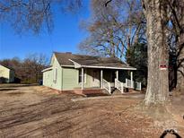Charming one-story house with a quaint front porch and mature trees, creating a peaceful and inviting curb appeal at 2124 W C St, Kannapolis, NC 28081