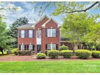 Charming two-story red brick home featuring a well-manicured lawn and established landscaping at 2217 Heath Lake Dr, Mint Hill, NC 28227