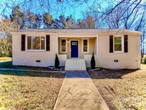 Charming brick home featuring a bright blue front door, two well-placed miniature evergreen trees, and traditional window shutters at 315 Dunham Ave, Salisbury, NC 28146
