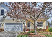 Charming yellow home featuring an attached garage, front porch, and mature tree in a well-maintained yard at 1131 Curry Way # 69, Matthews, NC 28104