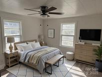 Bright bedroom with a ceiling fan, two windows, light colored furniture, and a comfortable bed at 142 S Ervin Ave, Newton, NC 28658
