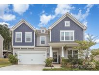 Charming two-story home with blue and gray accents, landscaped yard, and welcoming front porch at 205 Falls Cove Dr, Troutman, NC 28166