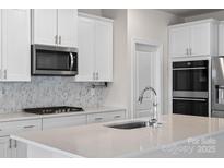 Modern kitchen with stainless steel appliances, white cabinetry, and a stylish tile backsplash at 3012 Seville St, Charlotte, NC 28214