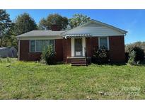 Charming single-story brick home featuring a covered front porch and an expansive, overgrown front yard at 4521 Fallston Rd, Shelby, NC 28150