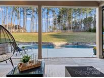 Inviting pool area with stone surround, lush green lawn, and tall trees providing privacy at 462 Barber Loop, Mooresville, NC 28117