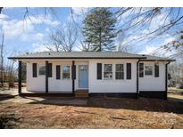 Charming home showcasing light blue front door, black shutters, and white siding under a partly cloudy sky at 523 Hickory Nut Ln, China Grove, NC 28023