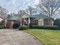 Beautiful brick home with lush landscaping and American flag waving in the front yard at 1217 12Th Fairway Nw Dr, Concord, NC 28027