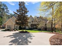 Stately home with a manicured lawn, circular driveway, and beautiful landscaping under a bright blue sky at 13215 Claysparrow Rd, Charlotte, NC 28278