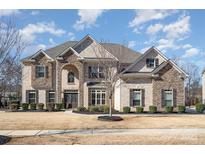 Stunning two-story home showcasing stone and brick details, complemented by a professionally landscaped front yard at 15411 Guthrie Dr, Huntersville, NC 28078