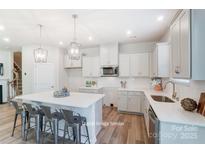 Bright kitchen features white cabinetry, stainless steel appliances, and a central island with barstool seating at 6419 Mallow Crossing Ln, Charlotte, NC 28213