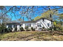 Quaint exterior view of the white-sided home exhibiting multiple windows and mature landscaping at 1116 Medlin Rd, Monroe, NC 28112