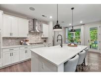 Modern kitchen boasts white cabinetry, stainless steel appliances, a large island with seating, and stylish pendant lighting at 138 Nicholson Ln, Mooresville, NC 28115