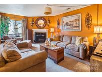 Cozy living room with a fireplace, comfortable seating, and warm, inviting decor on orange colored walls at 4811 Spring Lake Dr # C, Charlotte, NC 28212