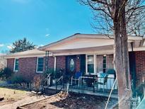 Charming brick home with a cozy front porch, iron railings, and inviting entrance with beautiful blue skies overhead at 5923 Charleston Ave, Kannapolis, NC 28081