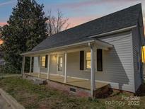 Charming home featuring a welcoming front porch with classic white pillars and black shuttered windows at 704 Mill St, Albemarle, NC 28001