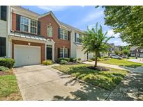 Well-maintained brick townhome featuring an attached garage, lush lawn, and mature landscaping at 140 N Arcadian Way, Mooresville, NC 28117