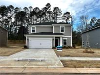 Charming two-story home featuring a two-car garage, gray siding, and beautifully landscaped front yard at 1411 Windy Park Dr, Stanley, NC 28164