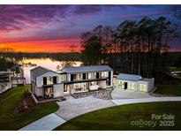 Stunning waterfront modern home with lush landscaping and a tranquil lake view at sunset at 2536 Brawley School Rd, Mooresville, NC 28117