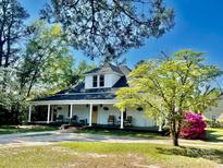 Charming white home with a full front porch, rocking chairs, and mature trees at 415 E Richland St, Kershaw, SC 29067