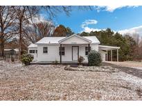 Charming white home featuring a covered carport, front porch, and landscaped yard dusted with snow at 5028 Wilgrove Mint Hill Rd, Mint Hill, NC 28227