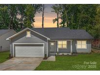 Charming single-story home with a well-manicured lawn, gray siding, and an attached one car garage at 5404 Maplewood Ln, Charlotte, NC 28227