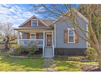 Charming home featuring a welcoming front porch, complemented by a beautiful front yard and natural stone pathway at 701 S Torrence St, Charlotte, NC 28204