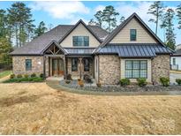 Inviting brick home featuring a covered front porch, manicured landscaping, and a charming, traditional design at 894 Abilene Ln, Fort Mill, SC 29715