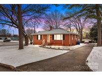 Charming red brick home with black shutters, landscaped yard and paved driveway, all dusted with a fresh coat of snow at 1401 Walker St, Salisbury, NC 28144
