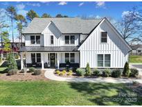 Beautiful two-story home with white siding, black trim, a manicured lawn and professional landscaping at 16709 Mckee Rd, Charlotte, NC 28278