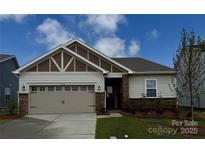 Charming single-story home with a two car garage, stone accents, manicured lawn, and inviting curb appeal at 2656 Tillman St, Monroe, NC 28112