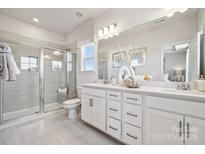 Modern bathroom features a glass shower, double vanity, and neutral tile flooring at 3218 Stelfox St, Charlotte, NC 28262
