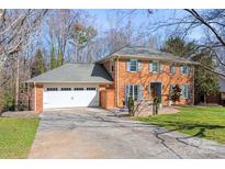 Charming brick home featuring a two-car garage, well-maintained lawn, and traditional architectural details at 1301 Charter Pl, Charlotte, NC 28211