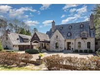 Stunning stone home featuring a porte-cochere, gabled roof, and lush landscaping for an elegant, timeless look at 20711 Bethel Church Rd, Cornelius, NC 28031