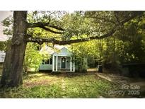 Charming home featuring a covered porch with a small yard surrounded by mature trees and greenery at 3016 Parkway Ave, Charlotte, NC 28208