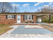 Charming red brick home with white trim, covered parking and cozy front patio seating area at 303 S Eastway Dr, Troutman, NC 28166