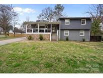 Charming two-story home featuring stone accents, a covered porch with ceiling fans, and a spacious front lawn at 3501 Winterfield Pl, Charlotte, NC 28205