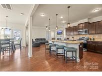 Bright kitchen featuring an island with seating, stainless steel appliances, and hardwood flooring at 13203 Caite Ridge Rd, Davidson, NC 28036