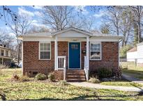 Charming brick home featuring a cozy porch and a vibrant blue front door at 1857 Brownstone St, Charlotte, NC 28216